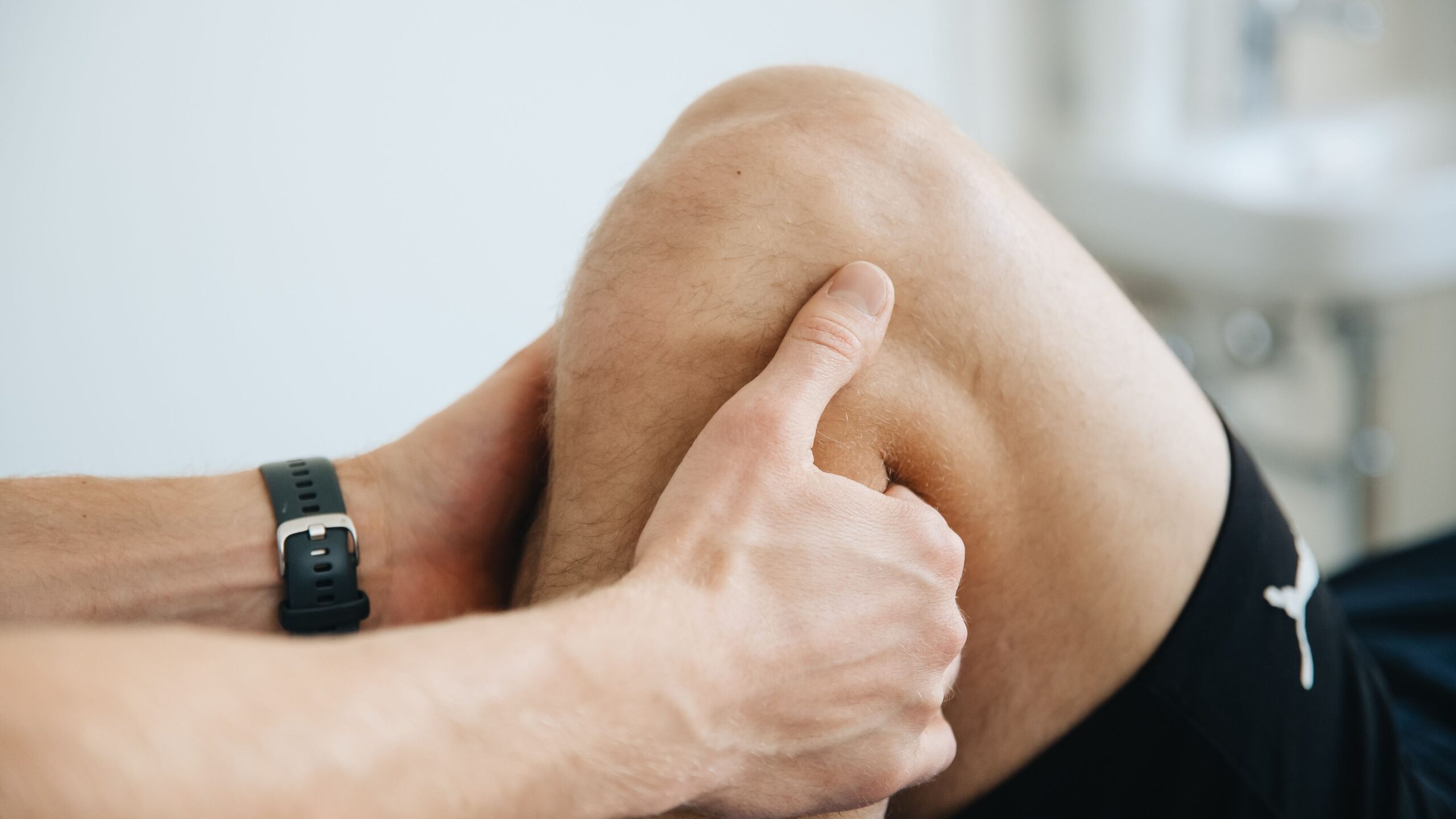 Physiotherapeut untersucht das Knie eines Patienten mit manueller Therapie